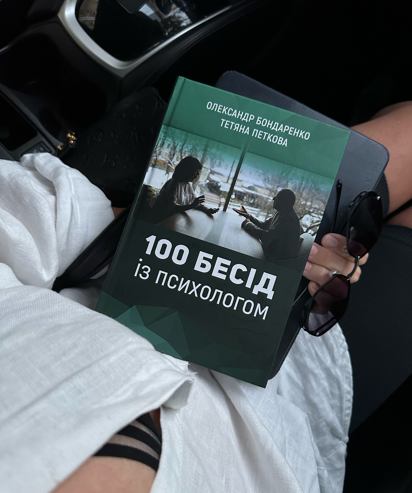 Обкладинка книги '100 бесід з психологом', зображена як книга на столі з ручкою і записною книжкою, символізуючи психотерапевтичні бесіди і особистісний розвиток."