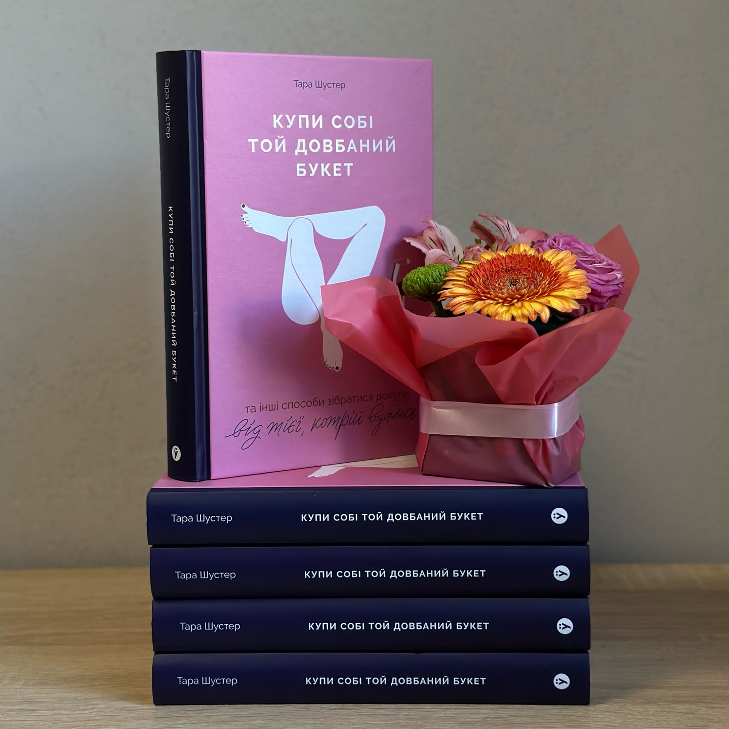 Стопка книг "Купи собі той довбаний букет" поруч із квітами Стопка книг "Купи собі той довбаний букет" поруч із квітами