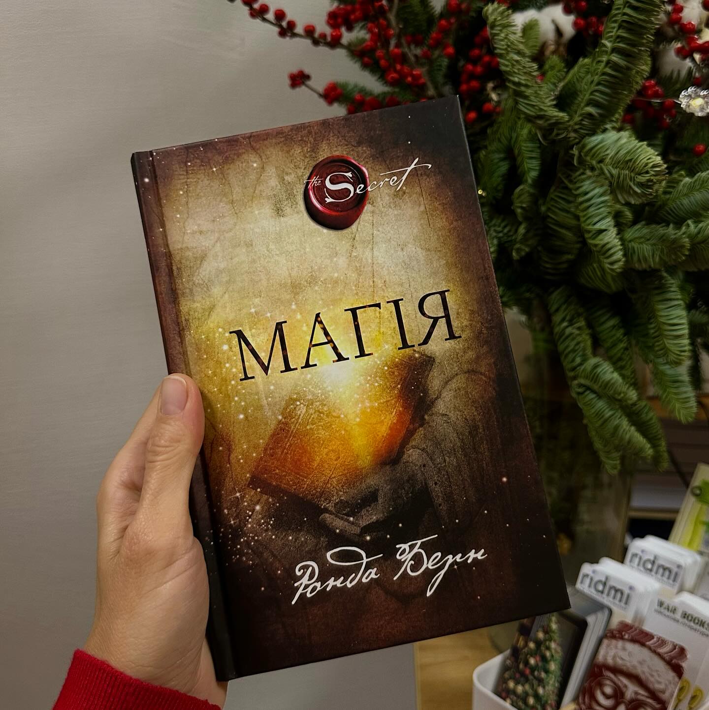 Книга «Магія» в руках у дівчини біля квітів Книга «Магія» в руках у дівчини біля квітів